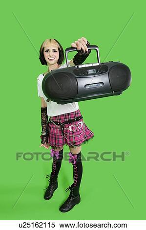 Portrait of young woman holding boom box over green background View Large Photo Image Stock Photography - Portrait of young woman holding boom box over green background. Fotosearch