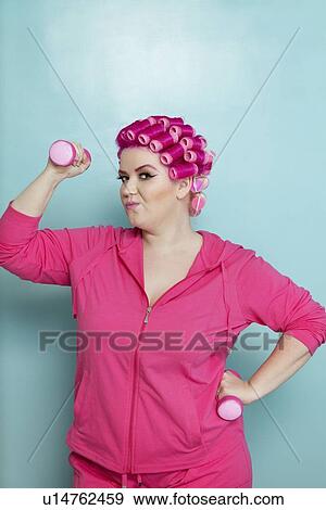 Stock Photo - Portrait of young woman lifting weights over colored background. Fotosearch