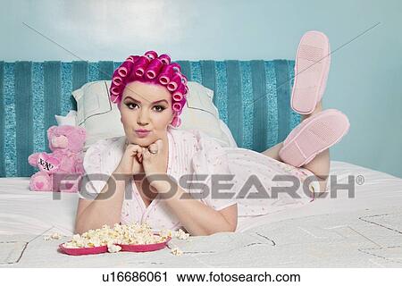 Portrait of young woman lying on bed with popcorn View Large Photo Image Stock Image - Portrait of young woman lying on bed with popcorn. Fotosearch