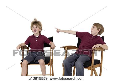 Pre-teen boy pointing at friend's hair while sitting on director's chair over white background View Large Photo Image Stock Photo - Pre-teen boy pointing at friend's hair while sitting on director's chair over white background. Fotosearch