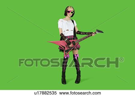 Stock Photography - Punk woman with guitar over green colored background. Fotosearch