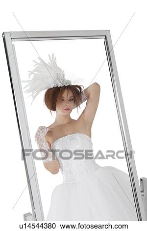 Stock Image - Reflection of young bride in mirror over white background. Fotosearch