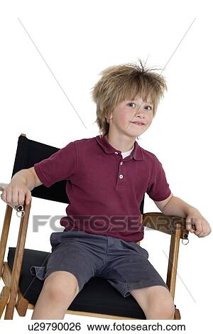 Stock Photograph - School boy sitting on director's chair over white background. Fotosearch
