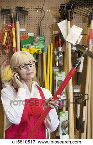Senior female employee holding gardening tool while using mobile phone View Large Photo Image Stock Photo - Senior female employee holding gardening tool while using mobile phone. Fotosearch