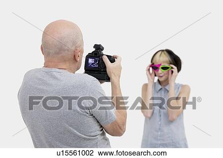 Stock Image - Senior photographer taking a photograph of fashion model during photo shoot. Fotosearch