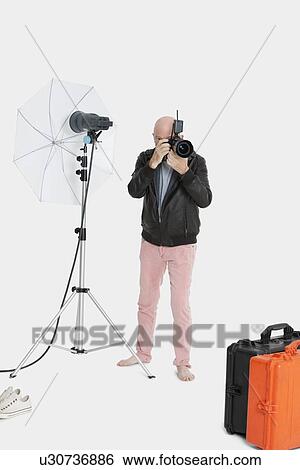 Stock Photograph - Senior photographer taking a photograph in studio. Fotosearch