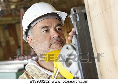 Serious male construction worker cutting wood with a power saw View Large Photo Image Stock Image - Serious male construction worker cutting wood with a power saw. Fotosearch
