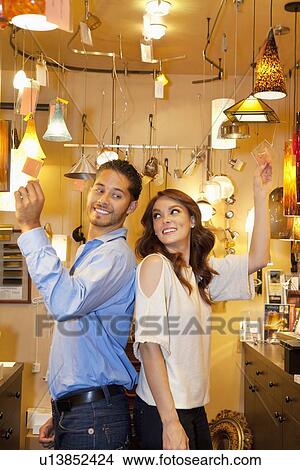 Side view of young couple standing back to back in lights store View Large Photo Image Picture - Side view of young couple standing back to back in lights store. Fotosearch