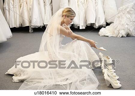 Side view of young woman in wedding dress confused while selecting footwear View Large Photo Image Stock Image - Side view of young woman in wedding dress confused while selecting footwear. Fotosearch