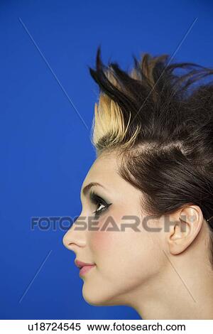 Stock Photography - Side view of young woman with spiked hair over colored background. Fotosearch