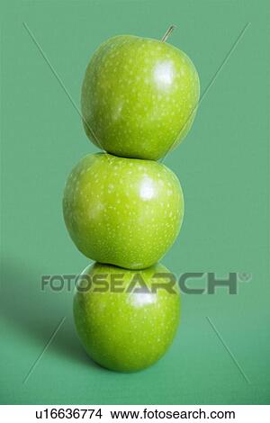 Picture - Stack of green apples over colored background. Fotosearch