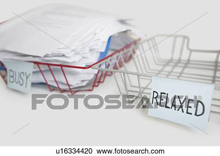 Stock Image - Stack of paperwork in busy tray with empty relaxed platter over white background. Fotosearch