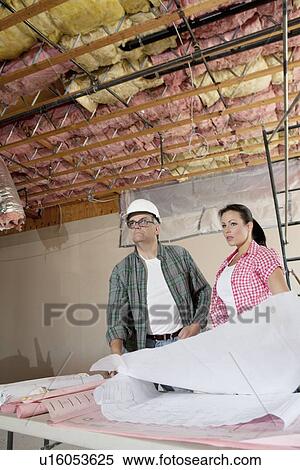 Team of architects looking away with blueprints at construction site View Large Photo Image Stock Photography - Team of architects looking away with blueprints at construction site. Fotosearch