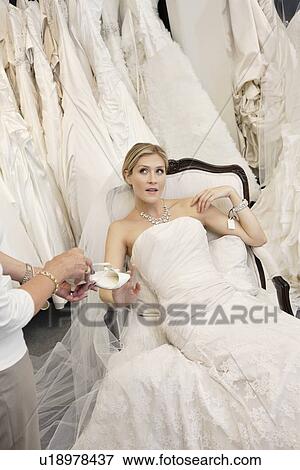 Tired young bride in wedding dress sitting while mother showing footwear View Large Photo Image Stock Photo - Tired young bride in wedding dress sitting while mother showing footwear. Fotosearch