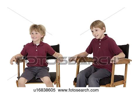 Stock Photography - Two happy school kids sitting on director's chair over white background. Fotosearch