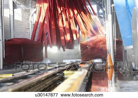 Stock Photo - Vehicle moving on conveyor going through cleaning in car wash. Fotosearch