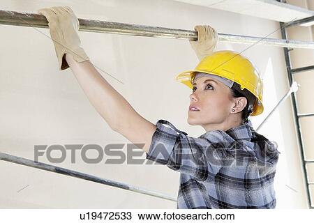 Woman worker placing rod on scaffold at construction site View Large Photo Image Stock Image - Woman worker placing rod on scaffold at construction site. Fotosearch