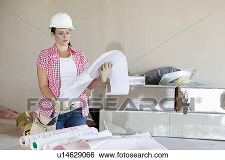 Young architect wearing hardhat looking building plans View Large Photo Image Stock Photograph - Young architect wearing hardhat looking building plans. Fotosearch