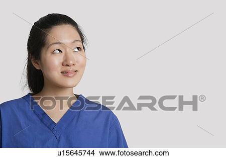 Young Asian female doctor looking up over gray background View Large Photo Image Picture - Young Asian female doctor looking up over gray background. Fotosearch