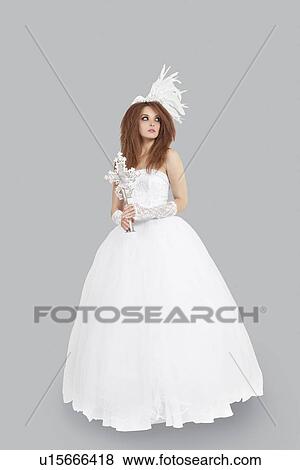Young bridge in wedding dress holding crucifix while looking away over light gray background View Large Photo Image Stock Photo - Young bridge in wedding dress holding crucifix while looking away over light gray background. Fotosearch