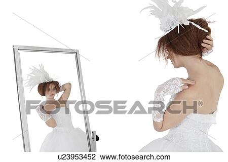 Young brunette bride in wedding gown looking at herself in mirror over white background View Large Photo Image Stock Image - Young brunette bride in wedding gown looking at herself in mirror over white background. Fotosearch