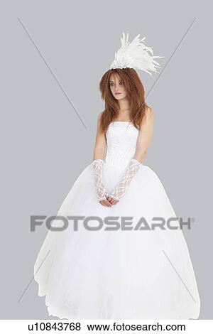 Young Brunette Bride Standing In Wedding Gown Over Light Gray