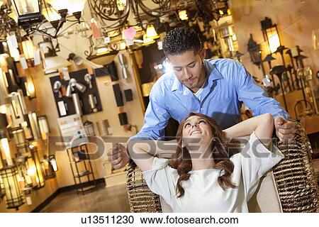 Stock Image - Young couple looking at each other in lights store. Fotosearch