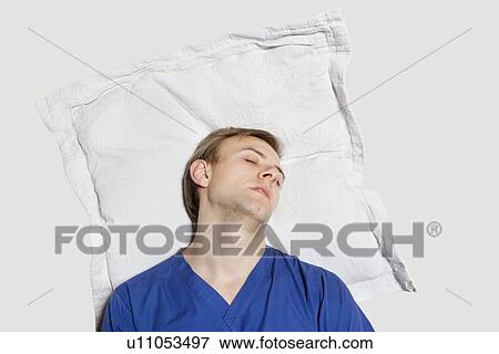 Young man reclined her head on pillow over colored background View Large Photo Image Stock Photo - Young man reclined her head on pillow over colored background. Fotosearch