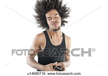 Stock Photograph - Young man shaking head while listening to mp3 player over white background. Fotosearch