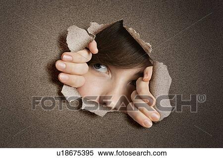 Stock Photography - Young Middle eastern woman peeking from ripped white paper hole. Fotosearch