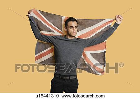 Young patriotic man lifting British flag over colored background View Large Photo Image Stock Image - Young patriotic man lifting British flag over colored background. Fotosearch