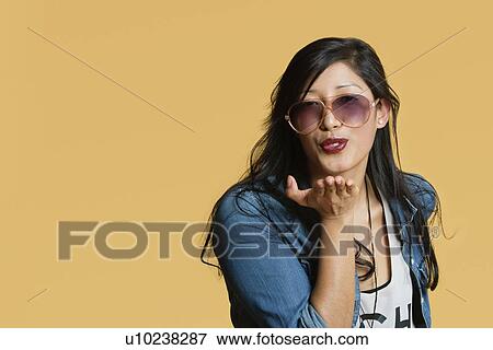 Young woman blowing kisses over colored background View Large Photo Image Stock Photo - Young woman blowing kisses over colored background. Fotosearch