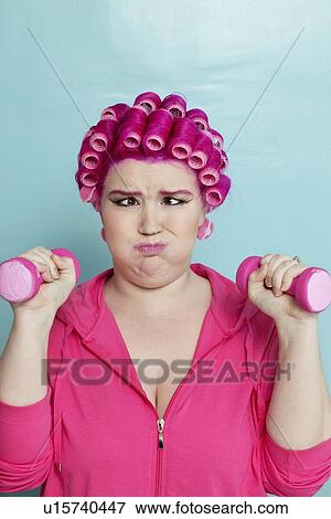 Young woman crossed eyes lifting dumbbell over colored background View Large Photo Image Stock Photo - Young woman crossed eyes lifting dumbbell over colored background. Fotosearch