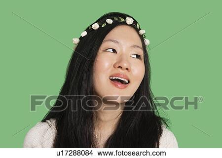 Young woman wearing hair ornament looking away over green background View Large Photo Image Picture - Young woman wearing hair ornament looking away over green background. Fotosearch
