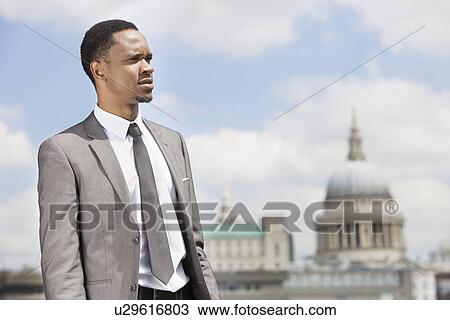 Stock Image - African American businessman looking away with St. Paul's Cathedral in the background. Fotosearch