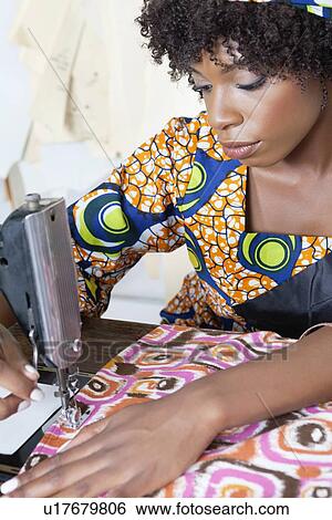 Stock Photograph - African American female tailor stitching patterned cloth on sewing machine. Fotosearch