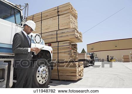 African American male contractor using tablet PC while standing by logging truck View Large Photo Image Stock Image - African American male contractor using tablet PC while standing by logging truck. Fotosearch