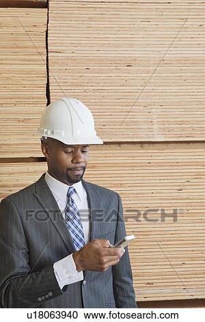 African American male engineer using cell phone with stacked wooden planks in background View Large Photo Image Stock Image - African American male engineer using cell phone with stacked wooden planks in background. Fotosearch