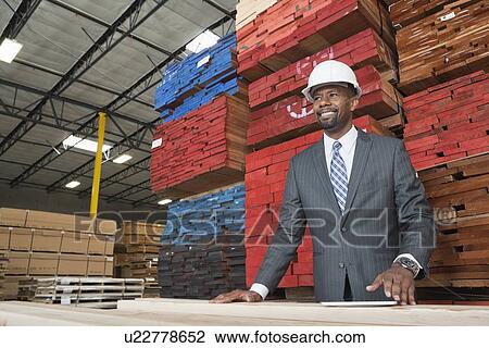 An African American male contractor standing in front of stacked wooden planks View Large Photo Image Stock Image - An African American male contractor standing in front of stacked wooden planks. Fotosearch