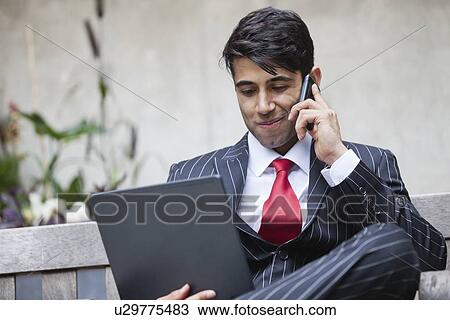 An Indian businessman using tablet PC while communicating on cell phone View Large Photo Image Stock Image - An Indian businessman using tablet PC while communicating on cell phone. Fotosearch