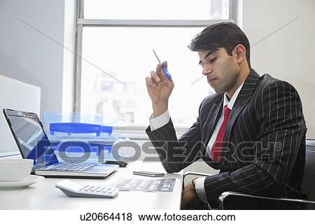 An Indian businessman working at office desk View Large Photo Image Stock Photo - An Indian businessman working at office desk. Fotosearch