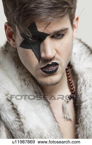 Angry young man with painted face wearing fur coat against gray background View Large Photo Image Stock Photo - Angry young man with painted face wearing fur coat against gray background. Fotosearch