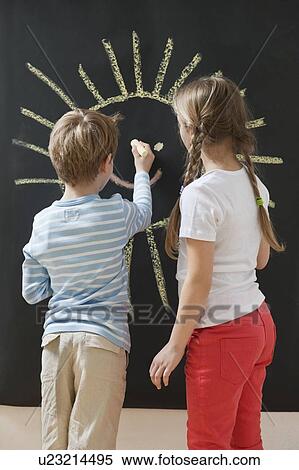 Back view of siblings drawing sun on blackboard View Large Photo Image Stock Photography - Back view of siblings drawing sun on blackboard. Fotosearch