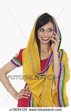 Beautiful Indian woman in traditional wear answering phone call over white background View Large Photo Image Picture - Beautiful Indian woman in traditional wear answering phone call over white background. Fotosearch