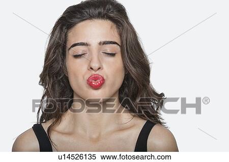 Beautiful woman puckering lips with eyes closed over gray background View Large Photo Image Stock Photography - Beautiful woman puckering lips with eyes closed over gray background. Fotosearch