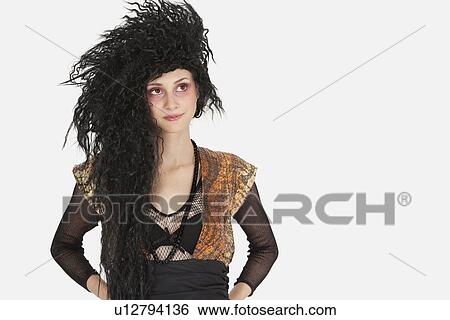 Stock Photograph - Beautiful young Goth woman with teased hair looking away over gray background. Fotosearch