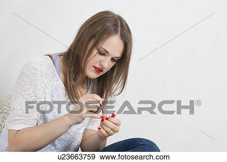 Stock Photo - Beautiful young woman applying nail paint. Fotosearch
