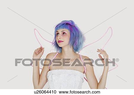 Beautiful young woman dressed as angel with dyed hair looking up against gray background View Large Photo Image Stock Image - Beautiful young woman dressed as angel with dyed hair looking up against gray background. Fotosearch