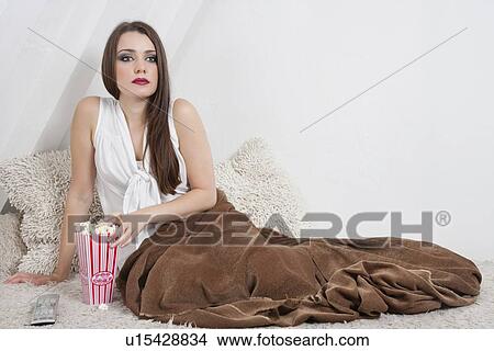 Beautiful young woman having popcorn while sitting in bed View Large Photo Image Picture - Beautiful young woman having popcorn while sitting in bed. Fotosearch