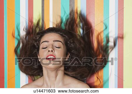 Beautiful young woman tossing hair against colorful striped background View Large Photo Image Stock Image - Beautiful young woman tossing hair against colorful striped background. Fotosearch